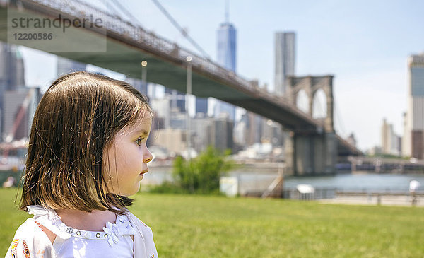USA  New York  Brooklyn  Porträt des kleinen Mädchens im Park mit Blick auf die Brooklyn Bridge im Hintergrund