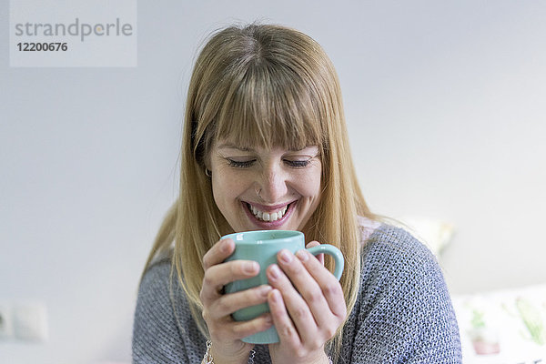 Porträt der lachenden jungen Frau mit Kaffeetasse