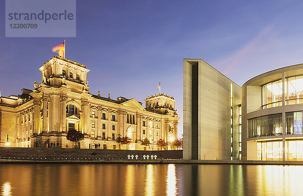 Deutschland  Berlin  Regierungsviertel  Reichstagsgebäude mit deutschen Fahnen und Paul-Loebe-Gebäude an der Spree am Abend