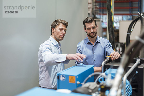 Zwei Männer diskutieren an der Maschine in der Fabrik.