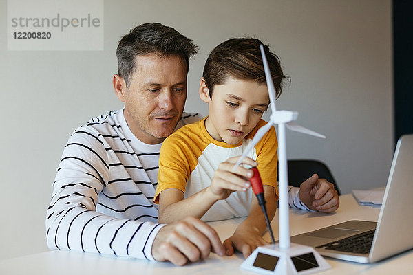 Vater und Sohn mit Laptop beim Zusammenbau des Windkraftanlagenmodells