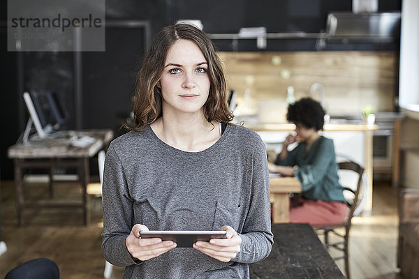 Porträt einer jungen Frau mit Tablette im modernen Büro