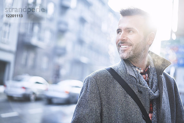 Porträt des lachenden Mannes auf der Stadtstraße im Winter