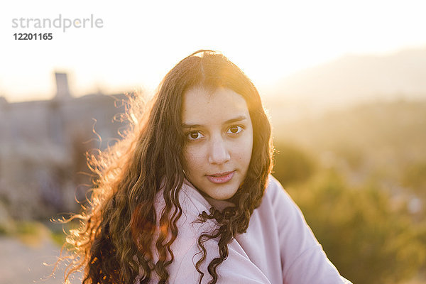 Porträt einer jungen Frau mit langen lockigen Haaren bei Sonnenuntergang