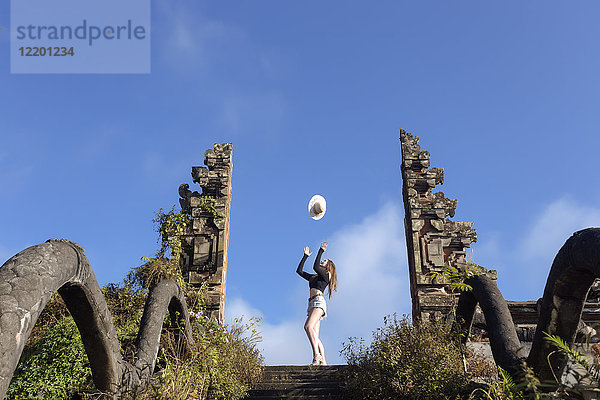Indonesien  Bali  junge Frau wirft ihren Hut in die Luft