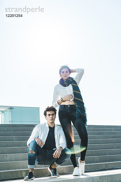 Porträt eines stilvollen jungen Paares auf einer Treppe im Freien