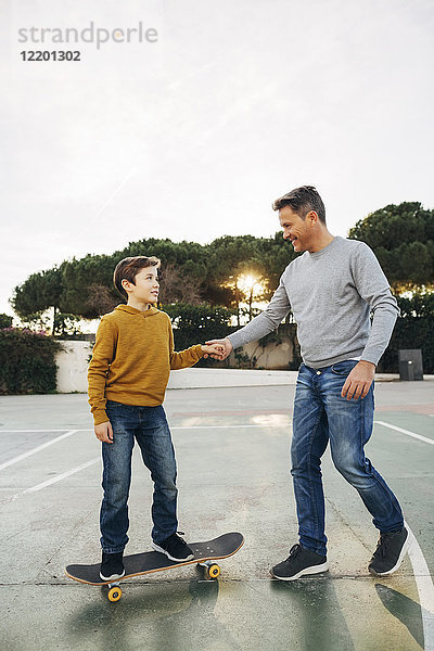 Vater assistiert Sohn beim Skateboardfahren