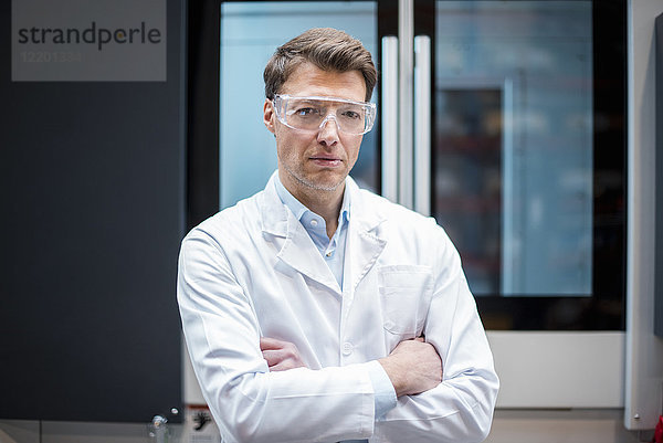 Porträt des Mannes mit Laborkittel und Schutzbrille an der Maschine