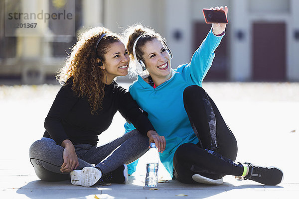 Zwei lächelnde  sportliche junge Frauen  die sich eine Pause gönnen.