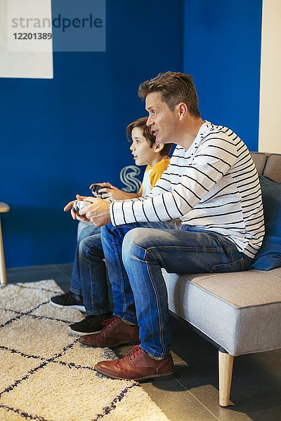 Vater und Sohn spielen Videospiel auf der Couch zu Hause