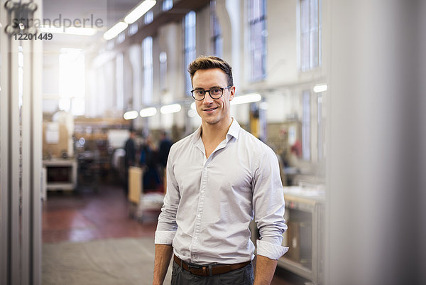 Porträt eines lächelnden jungen Geschäftsmannes in der Fabrik