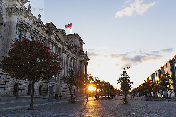 Deutschland  Berlin  Regierungsviertel  Reichstagsgebäude mit deutschen Fahnen und Paul-Loebe-Gebäude bei Sonnenuntergang