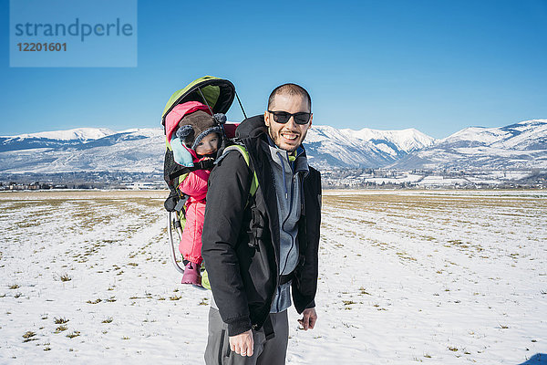 Spanien  Puigcerda  Vater mit Mädchen im Kindertragerucksack bei einer Winterwanderung