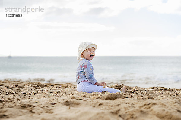 Spanien  Lanzarote  lachendes Mädchen am Strand sitzend