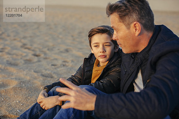 Vater und Sohn am Strand sitzend