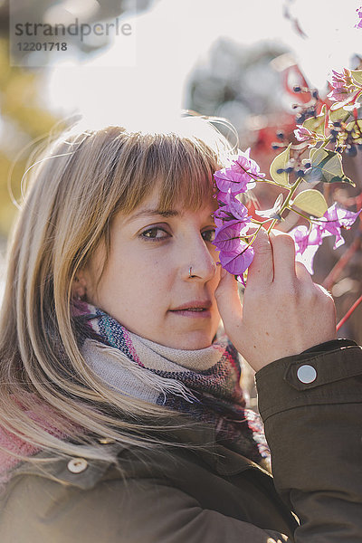 Porträt einer Frau  die im Freien Blumen riecht.
