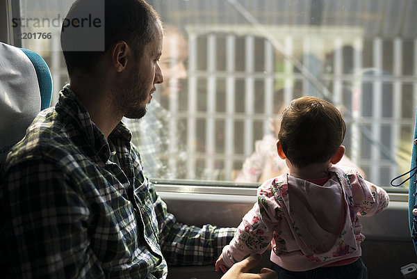 Vater und Mädchen reisen mit dem Zug und schauen aus dem Fenster.