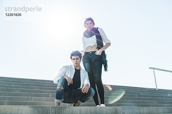 Porträt eines stilvollen jungen Paares auf einer Treppe im Freien