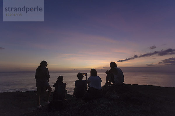 Indonesien  Bali  Lembonganische Insel  Freunde an der Meeresküste in der Abenddämmerung