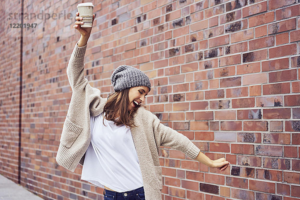 Glückliche Frau mit Kaffee zum Singen und Tanzen auf der Straße