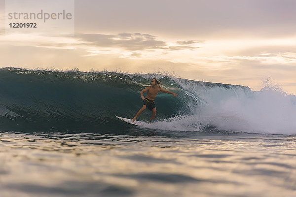 Indonesien  Sumatra  Surfer auf einer Welle bei Sonnenuntergang