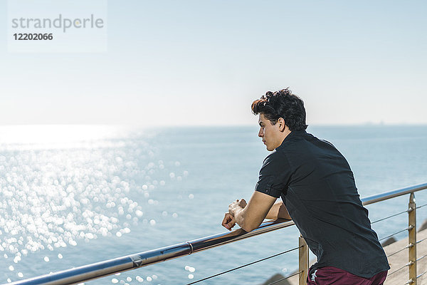 Junger Mann an der Küste mit Blick auf das Meer