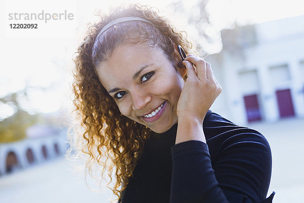 Porträt einer lächelnden jungen Frau im Freien mit Kopfhörer