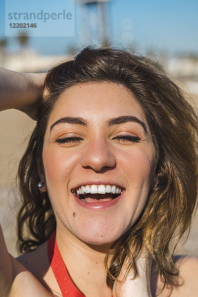 Porträt einer lachenden jungen Frau am Strand