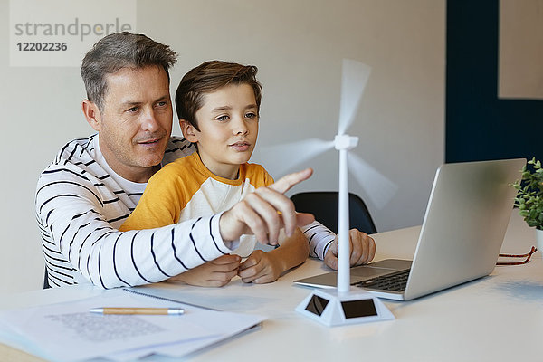 Vater und Sohn mit Laptop testen Windkraftanlage Modell