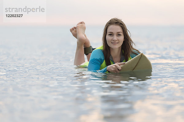 Indonesien  Bali  junge Frau auf dem Surfbrett liegend