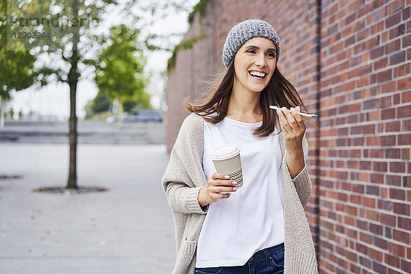 Porträt der glücklichen Frau mit Kaffee zum Telefonieren