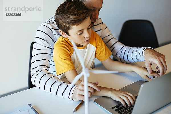 Vater und Sohn mit Laptop neben dem Windkraftanlagenmodell