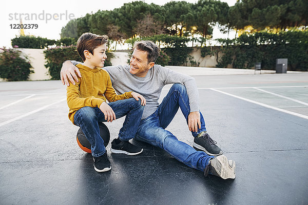 Vater umarmt Sohn auf Basketballfeld