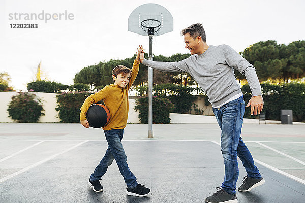 Vater und Sohn High Fiving auf dem Basketball-Außenplatz
