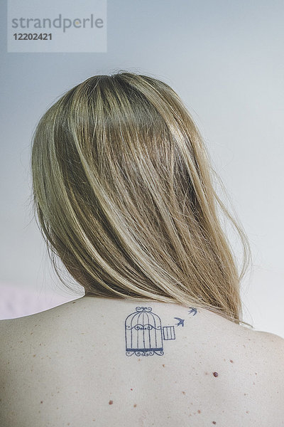 Rückansicht der blonden Frau mit Tattoo am Hals