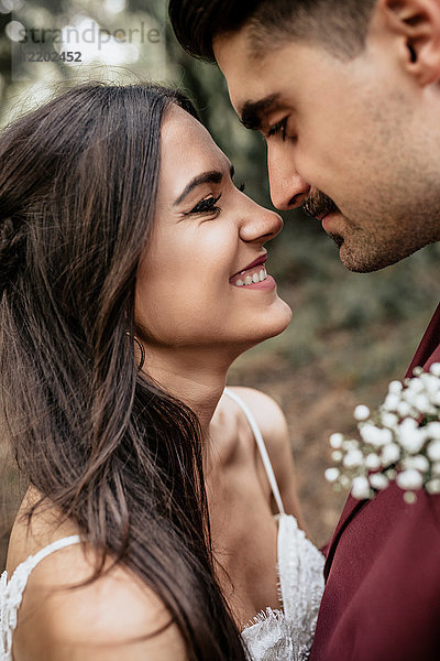 Porträt einer fröhlichen und lächelnden Braut  die einen Mann mit Schnurrbart im Freien ansieht.