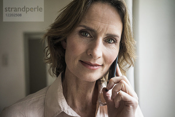Porträt der lächelnden reifen Frau auf dem Handy