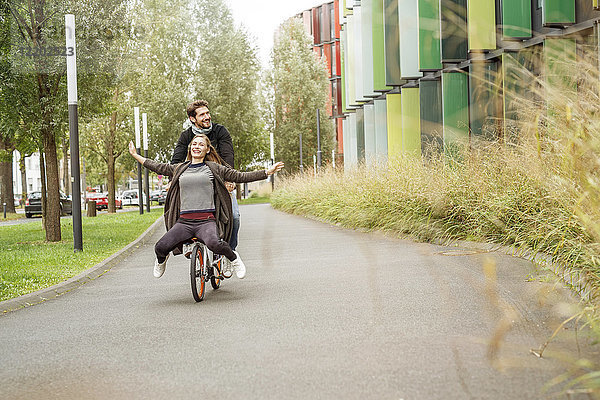 Ein glückliches Paar auf einem Fahrrad auf einem Weg