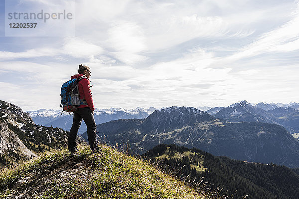 Österreich  Tirol  junge Frau in der Berglandschaft stehend mit Blick auf die Landschaft