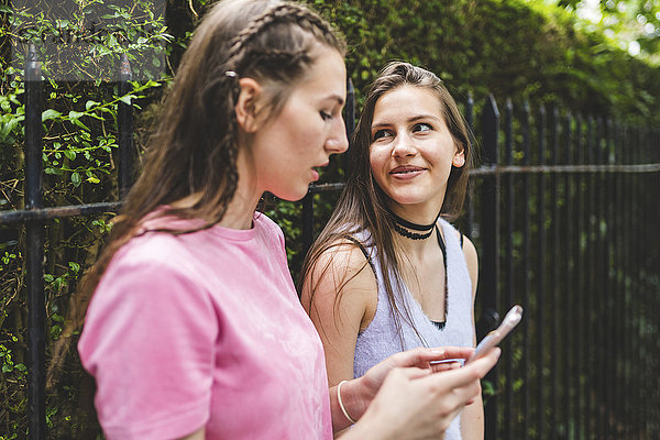 Zwei Teenagermädchen mit Handy im Freien