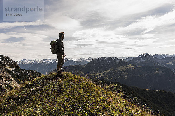 Österreich  Tirol  junger Mann steht in der Berglandschaft und schaut auf die Aussicht