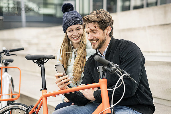 Lächelndes Paar mit Fahrrädern und Handy in der Stadt