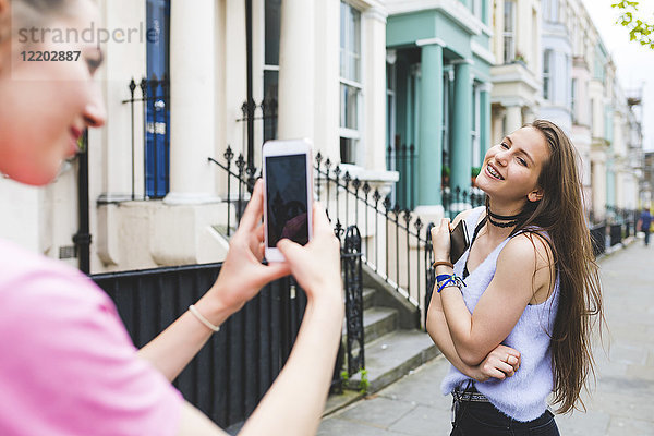 Junge Frau macht Handyfoto von Teenagermädchen in der Stadt