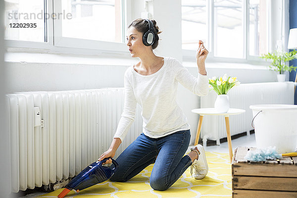 Frau zu Hause mit Kopfhörern  die den Boden saugen.