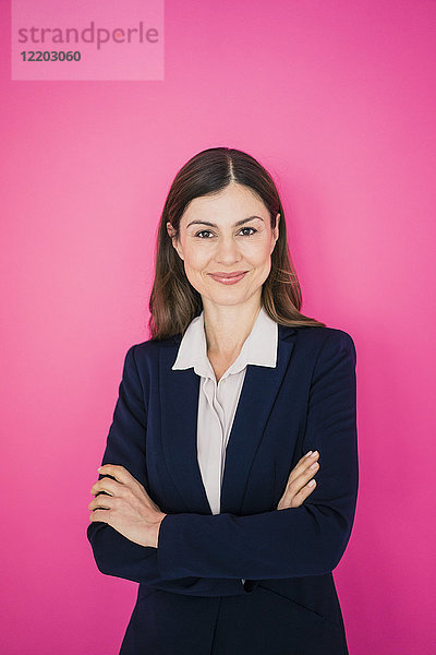 Porträt einer selbstbewussten Geschäftsfrau vor rosa Wand
