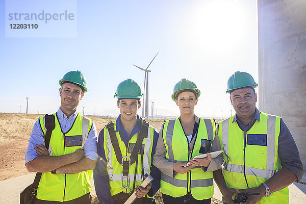 Porträt von vier lächelnden Ingenieuren auf einem Windpark