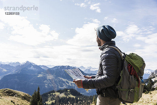 Österreich  Tirol  junger Mann mit Karte in Berglandschaft