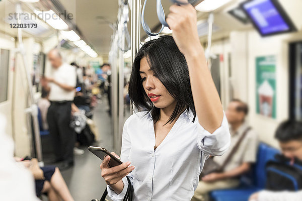Geschäftsfrau mit Handy in der U-Bahn