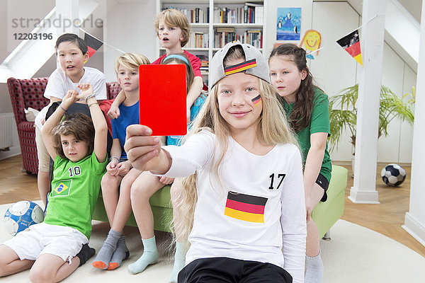 Mädchen zeigt rote Karte vor Freunden  schaut sich die Fußballweltmeisterschaft an