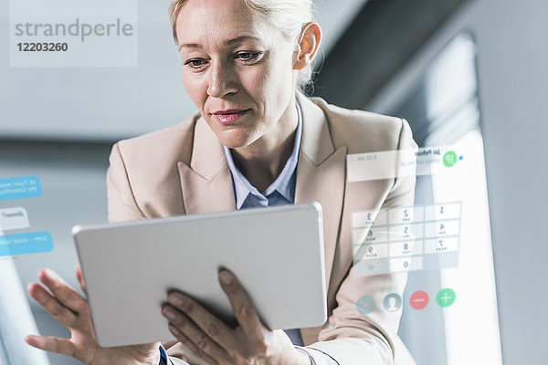 Geschäftsfrau im Büro sitzend  mit digitalem Tablett
